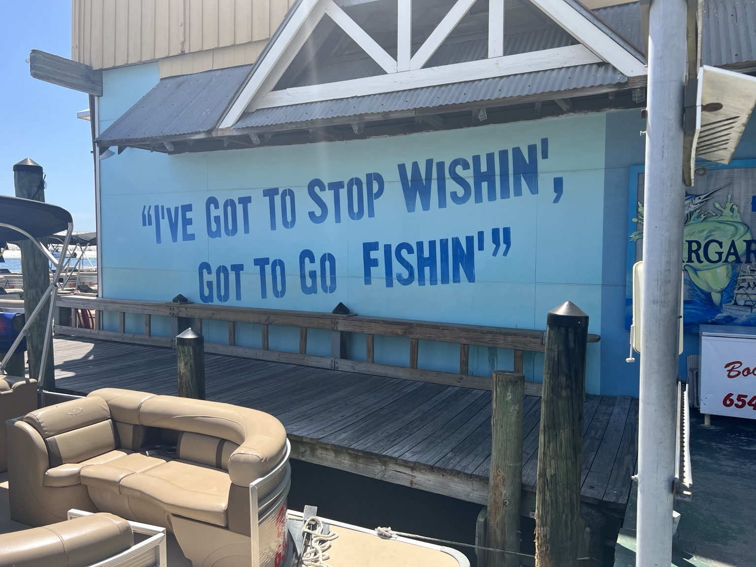 A waterfront sign reading I've got to stop wishin', got to go fishin'